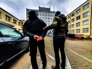 Zatrzymany prowadzony przez plac przez nieumundurowanego policjanta