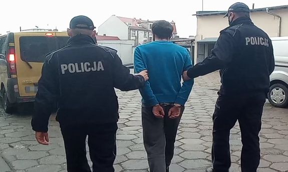 umundurowani policjanci prowadzą zatrzymanego mężczyznę