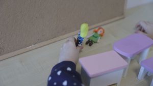 dziewczynka trzyma w ręku lalki, jedna z nich leży na biurku
