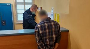 zatrzymany mężczyzna stojący tyłem i policjant