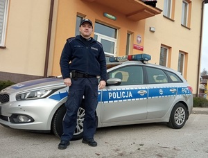 umundurowany policjant stoi przed radiowozem