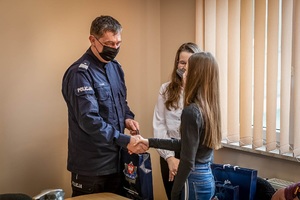 policjant gratuluje dziewczynkom wzorowej postawy i wezwania szybkiej pomocy dla potrzebującego