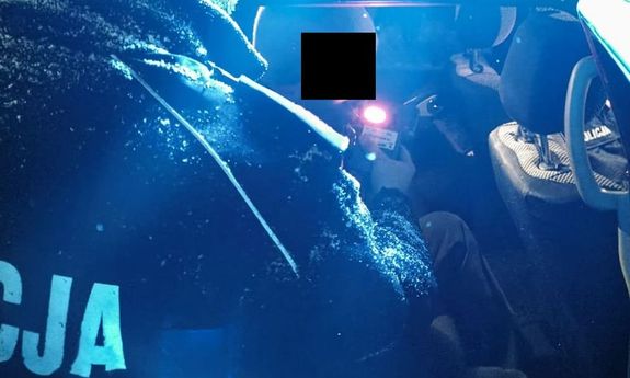 policjant przykłada alkomat do ust zatrzymanemu siedzącemu w radiowozie