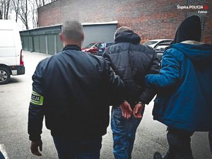 dwaj policjanci prowadzą zatrzymanego mężczyznę