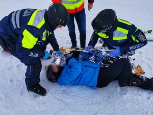 dwóch policjantów udziela pomocy poszkodowanemu mężczyźnie