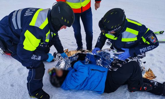 dwóch policjantów udziela pomocy poszkodowanemu mężczyźnie