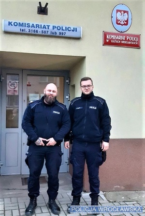 dwaj umundurowani policjanci stoją na tle budynku komisariatu