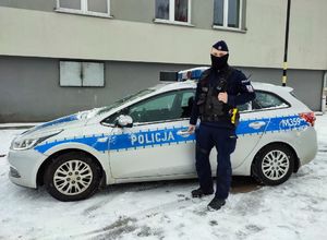 policjant stoi przy radiowozie