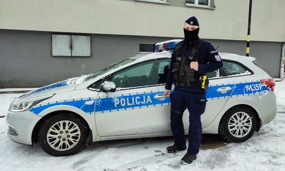 policjant stoi przy radiowozie