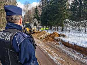 umundurowani policjanci zabezpieczają budowę zapory na granicy z Białorusią, patrolują i obserwują rejon oraz dbają o bezpieczeństwo osób wykonujących prace budowlane na granicy.