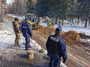 umundurowani policjanci zabezpieczają budowę zapory na granicy z Białorusią, patrolują i obserwują rejon oraz dbają o bezpieczeństwo osób wykonujących prace budowlane na granicy.
