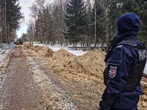 umundurowani policjanci zabezpieczają budowę zapory na granicy z Białorusią, patrolują i obserwują rejon oraz dbają o bezpieczeństwo osób wykonujących prace budowlane na granicy.