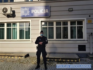 umundurowany policjant stoi przed budynkiem komisariatu Policji