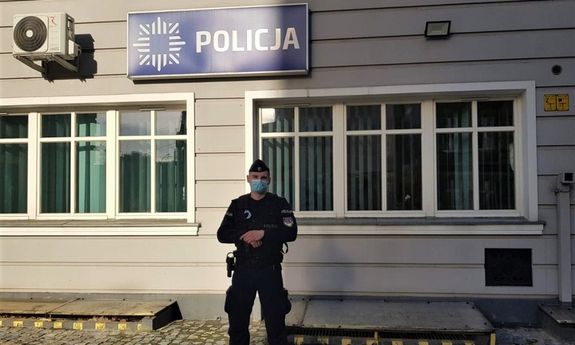 umundurowany policjant stoi przed budynkiem komisariatu Policji