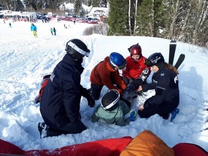 funkcjonariusze wraz z ratownikami GOPR udzielają pomocy poszkodowanemu narciarzowi