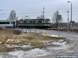 przejeżdżający pociąg i opuszczony szlaban na przejeździe kolejowym