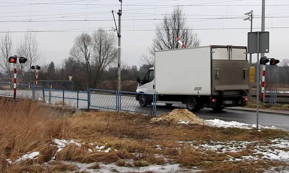 Szlaban na dachu ciężarowego Iveco, który wjechał na przejazd kolejowy pomimo czerwonego światła i opuszczającego się szlabanu