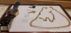 skradziony zegarek oraz złoty łańcuszek zabezpieczony przez policjantów na ladzie sklepowej