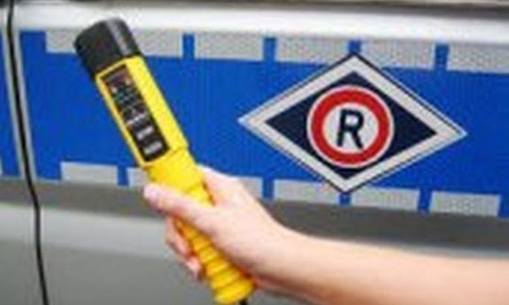 trzymane w dłoni alcoblow, z tyłu widać logo ruchu drogowego z boku radiowozu