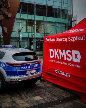 tył policyjnego radiowozu i czerwony namiot DKMS