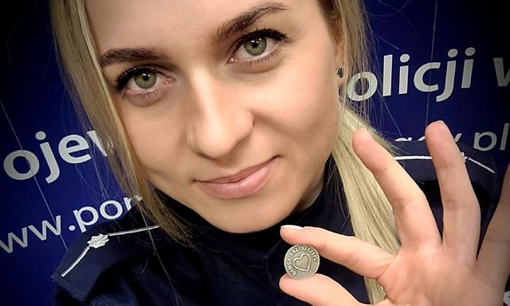 umundurowana policjantka trzymając w dłoni przypinkę dawcy przeszczepu