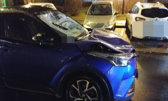 uszkodzony samochód osobowy, w tle stoją zaparkowane inne pojazdy