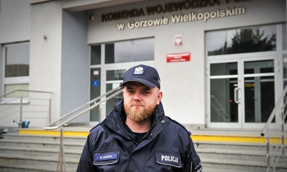 Umundurowany policjant przed budynkiem komendy Policji