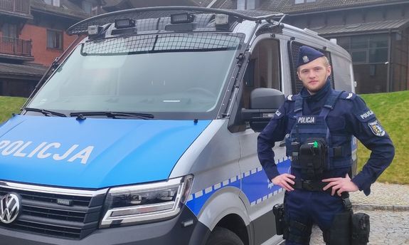 umundurowany policjant stoi przy radiowozie