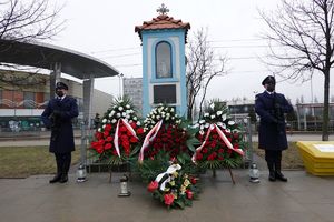 Wieńce przed kapliczką i dwaj funkcjonariusze pełniący honorową wartę