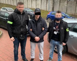 dwaj nieumundurowani policjanci prowadzą zatrzymanego