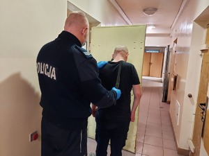 umundurowany policjant z zatrzymanym w drzwiach policyjnej celi