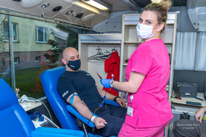 policjant siedzi na fotelu i oddaje krew, przy nim stoi pielęgniarka w różowym ubraniu