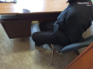 zatrzymany mężczyzna siedzi na krześle przy biurku