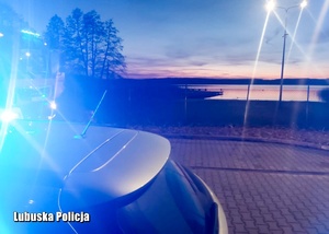widok na wodę, obok stoi radiowóz policyjny