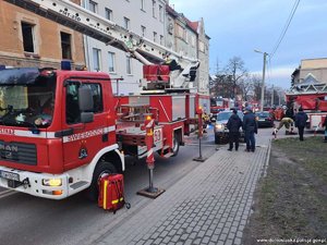 gaszenie pożaru, widoczne wozy strażackie przed budynkiem