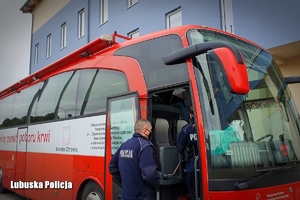 umundurowany policjant stoi przed mobilnym punktem krwiodawstwa