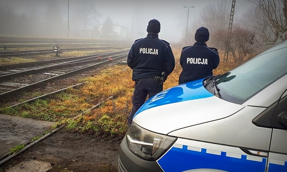 Policjanci przy radiowozie i torowisku