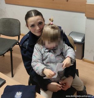 policjantka siedzi z dziewczynką na kolanach
