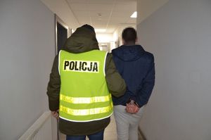 policjant prowadzi zatrzymanego mężczyznę