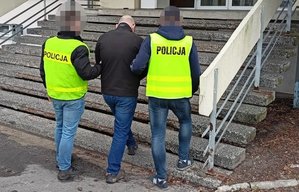 dwaj policjanci prowadzą zatrzymanego mężczyznę