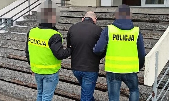 dwaj policjanci prowadzą zatrzymanego mężczyznę