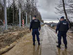 policjanci stoją przy zaporze granicznej