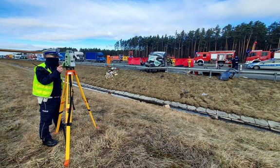 policjant z ruchu drogowego robiący pomiary na autostradzie a4 po wypadku busa