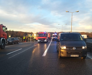 miejsce wypadku drogowego, w tle wóz strażacki i karetka pogotowia