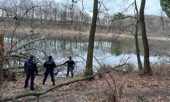 policjanci przeszukują teren nad wodą