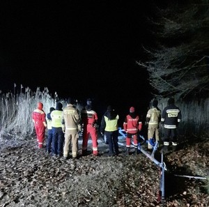 policjanci, strażacy i ratownicy WOPR stoją nad brzegiem rzeki