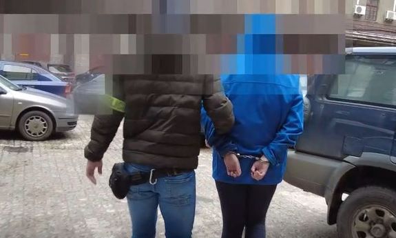 policjant prowadzi zatrzymaną osobę