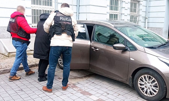 policjanci z zatrzymanym mężczyzną przy samochodzie osobowym