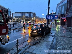 rozbity samochód osobowy, który uderzył w lampę, obok stoją strażacy