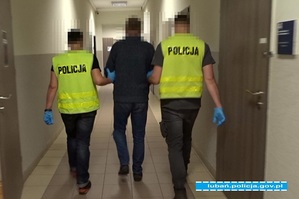 dwaj policjanci prowadzą zatrzymanego mężczyznę